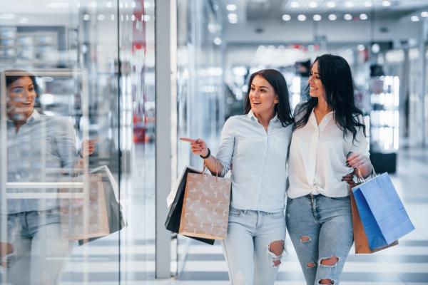 Two young women holding shopping bags in a mall.